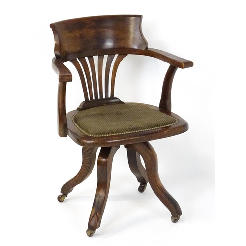 1843 - A late 19thC / early 20thC revolving captains chair with a fanned back splat, upholstered seat and b... 