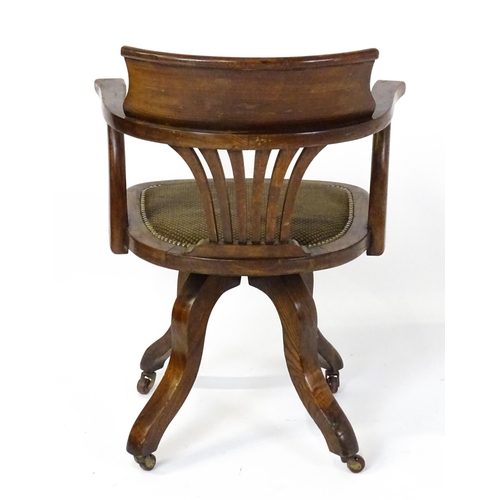 1843 - A late 19thC / early 20thC revolving captains chair with a fanned back splat, upholstered seat and b... 