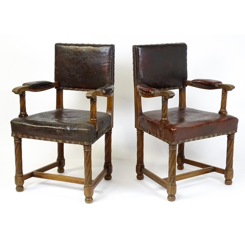 1863 - A pair of late 19thC / early 20thC leather upholstered armchairs with swept arms and brass detailing... 