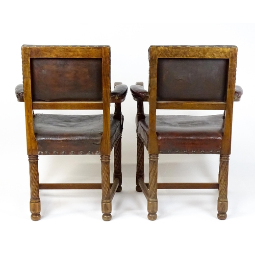 1863 - A pair of late 19thC / early 20thC leather upholstered armchairs with swept arms and brass detailing... 