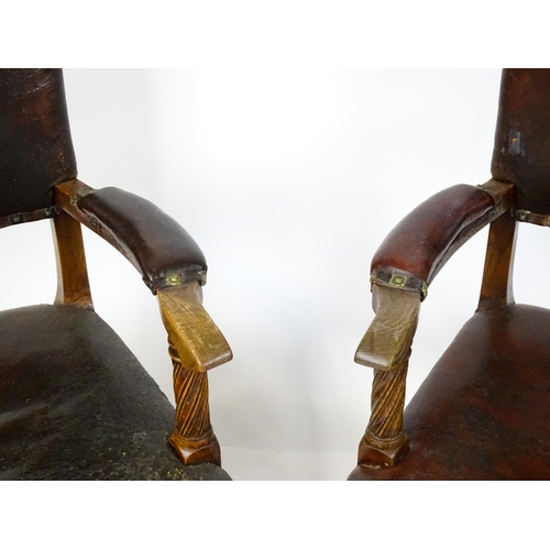 1863 - A pair of late 19thC / early 20thC leather upholstered armchairs with swept arms and brass detailing... 