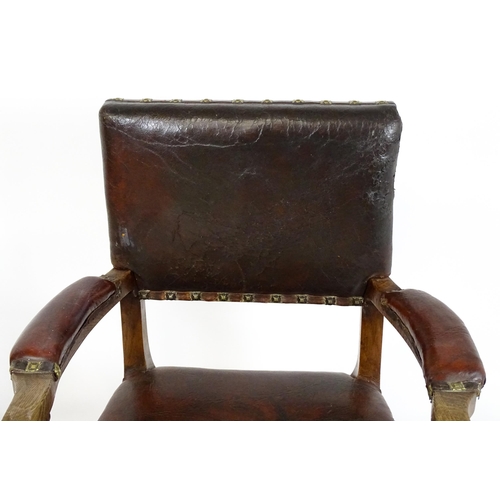 1863 - A pair of late 19thC / early 20thC leather upholstered armchairs with swept arms and brass detailing... 