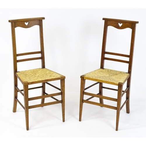 1865 - A pair of Arts & Crafts oak side chairs with shaped top rails pierced with heart motifs, the chairs ... 