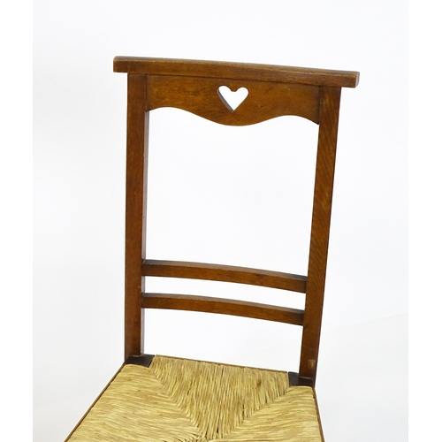 1865 - A pair of Arts & Crafts oak side chairs with shaped top rails pierced with heart motifs, the chairs ... 