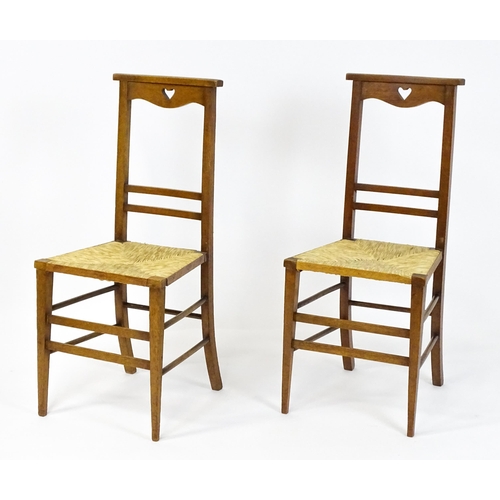 1865 - A pair of Arts & Crafts oak side chairs with shaped top rails pierced with heart motifs, the chairs ... 