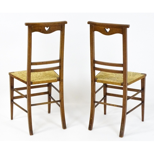 1865 - A pair of Arts & Crafts oak side chairs with shaped top rails pierced with heart motifs, the chairs ... 