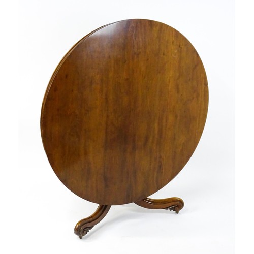 1895 - A Victorian mahogany breakfast / dining table with a round tilt op above a turned pedestal raised on... 