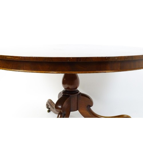 1895 - A Victorian mahogany breakfast / dining table with a round tilt op above a turned pedestal raised on... 