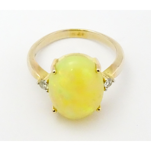 837 - A 9ct gold ring set with central opal cabochon flanked by diamonds. Ring size approx. P