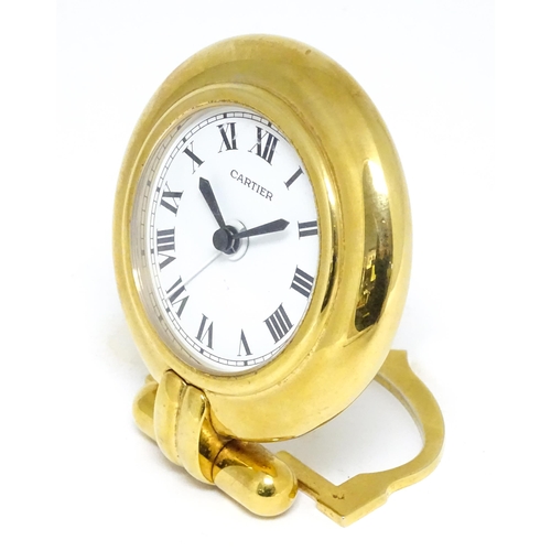 1658 - A Cartier brass cased alarm clock with quartz movement, the white dial with Roman numerals and signe... 