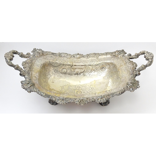 630 - A large George III silver twin handled dish with floral and C scroll decoration and raised on four l... 