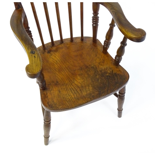 1868 - A late 19thC stick back Windsor chair with swept arms, a shaped elm seat and raised on four turned t... 