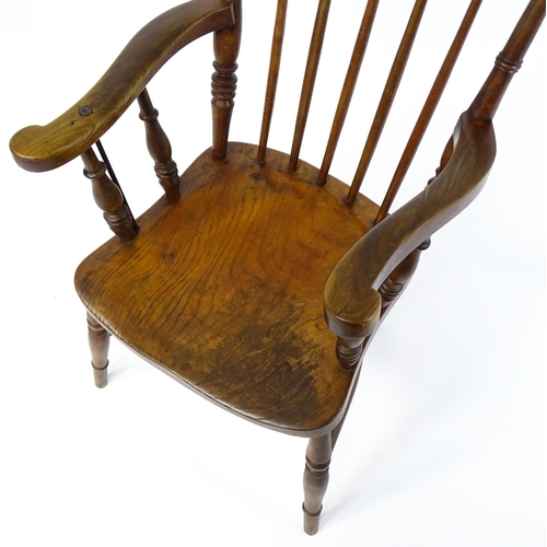 1868 - A late 19thC stick back Windsor chair with swept arms, a shaped elm seat and raised on four turned t... 