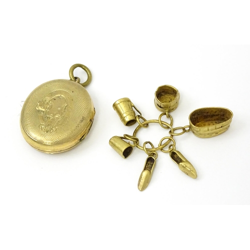 980 - A yellow metal locket with engraved decoration. Together with various yellow and gilt metal charms t... 