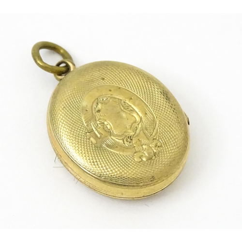 980 - A yellow metal locket with engraved decoration. Together with various yellow and gilt metal charms t... 