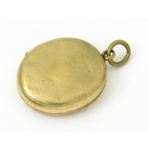 980 - A yellow metal locket with engraved decoration. Together with various yellow and gilt metal charms t... 