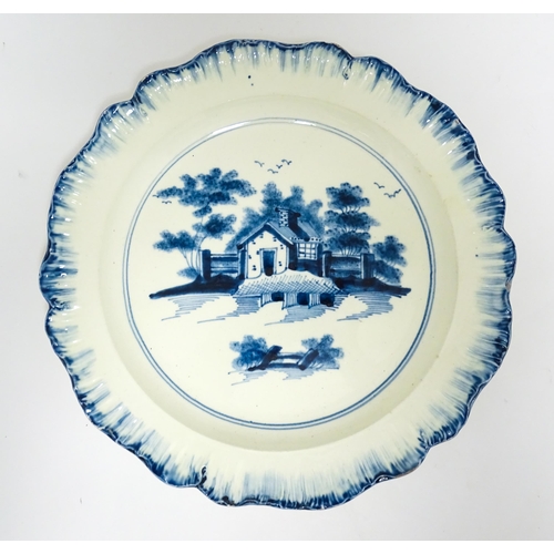 63 - An English blue and white plate with feather edge with hand painted decoration depicting a cottage i... 