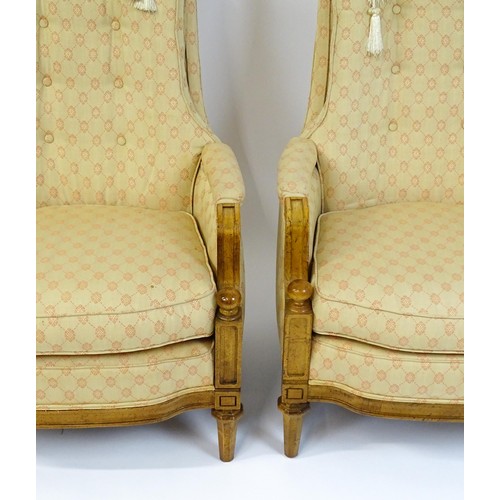 1831 - A pair of  20thC armchairs surmounted by brass finials, the chairs having deep buttoned cushions, in... 