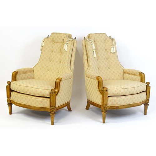 1831 - A pair of  20thC armchairs surmounted by brass finials, the chairs having deep buttoned cushions, in... 