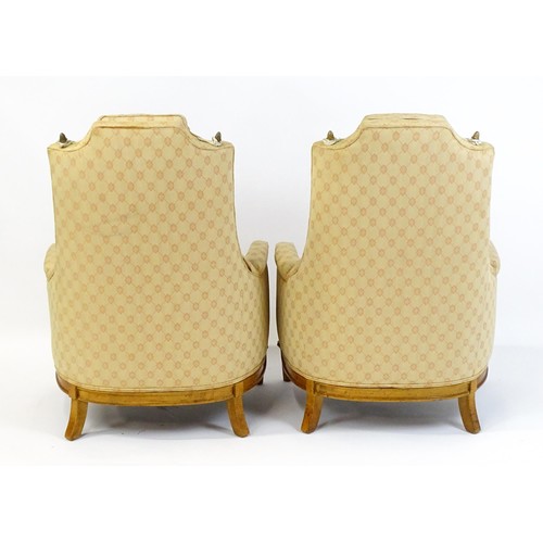 1831 - A pair of  20thC armchairs surmounted by brass finials, the chairs having deep buttoned cushions, in... 