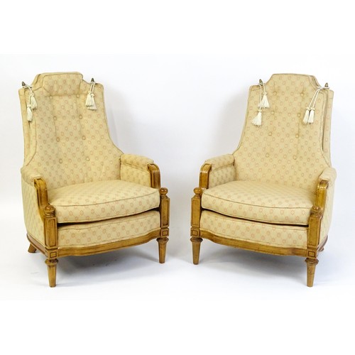 1831 - A pair of  20thC armchairs surmounted by brass finials, the chairs having deep buttoned cushions, in... 