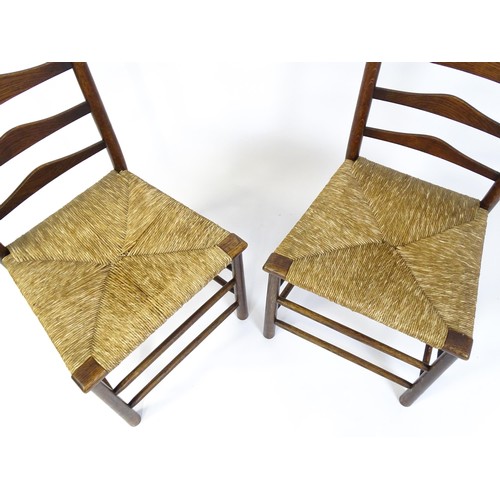 1833 - A pair of late 19thC Arts & Crafts ladderback chairs with graduated back rails above envelope rush s... 