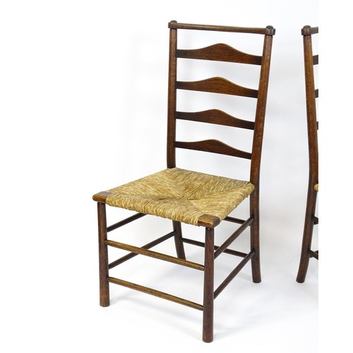 1833 - A pair of late 19thC Arts & Crafts ladderback chairs with graduated back rails above envelope rush s... 