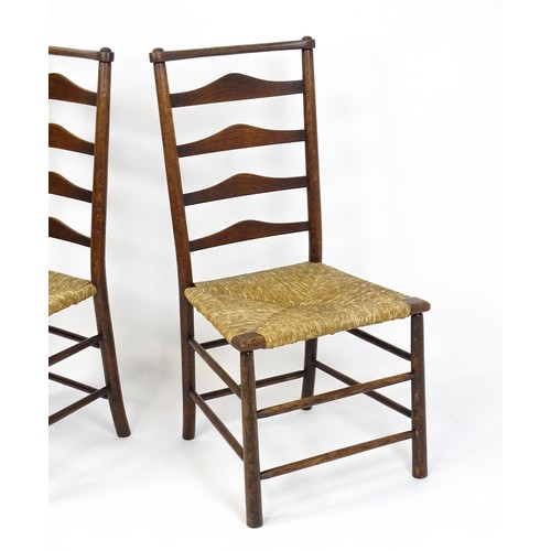 1833 - A pair of late 19thC Arts & Crafts ladderback chairs with graduated back rails above envelope rush s... 