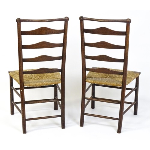 1833 - A pair of late 19thC Arts & Crafts ladderback chairs with graduated back rails above envelope rush s... 