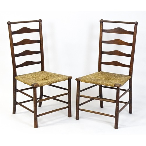 1833 - A pair of late 19thC Arts & Crafts ladderback chairs with graduated back rails above envelope rush s... 