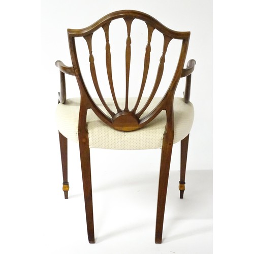 1862A - A George III mahogany Hepplewhite library chair with a shield shaped backrest and carved floral deta... 