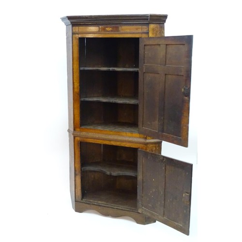 1718A - A mid / late 18thC oak double corner cupboard with a moulded cornice above a satinwood inlaid frieze... 