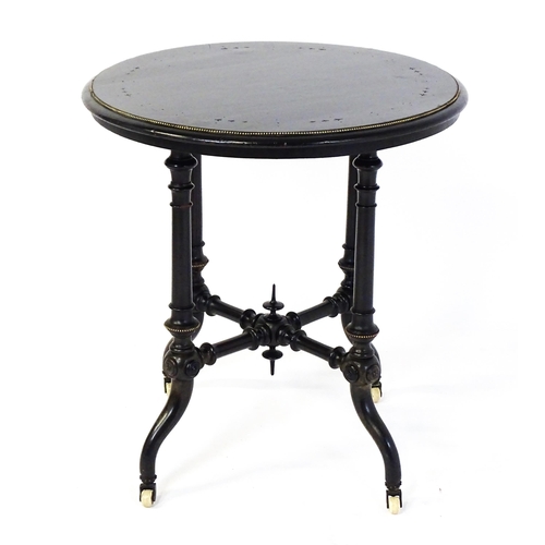 1869 - A Victorian ebonised occasional table with a circular brass studded top above four turned tapering l... 