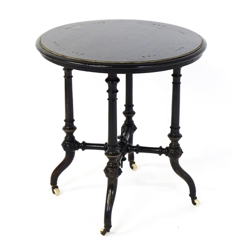 1869 - A Victorian ebonised occasional table with a circular brass studded top above four turned tapering l... 