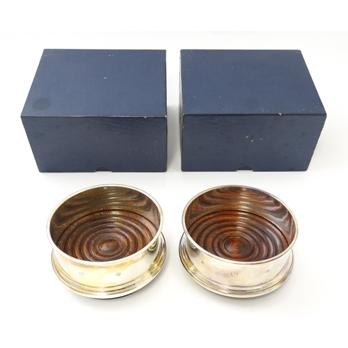 629 - A match pair of silver bottle coasters with turned wooden bases hallmarked Birmingham 1988 / 1989, m... 