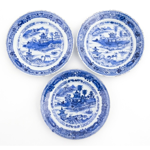 15 - Three Chinese blue and white plates, each decorated with a river landscape with pagoda style buildin... 