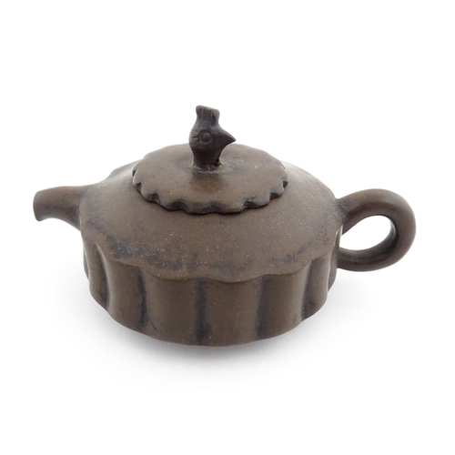 10 - A small Chinese Yixing teapot of lobed form, the lid with bird head finial. Character marks under li... 