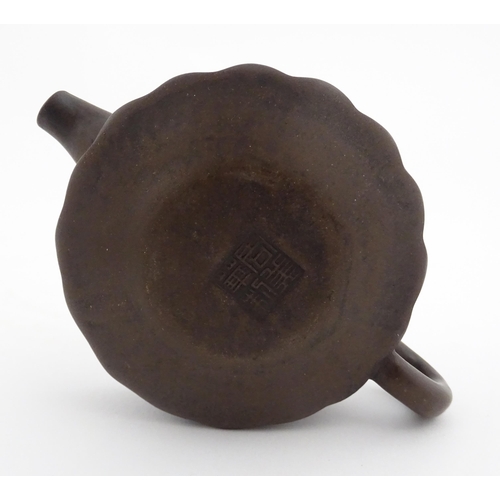 10 - A small Chinese Yixing teapot of lobed form, the lid with bird head finial. Character marks under li... 