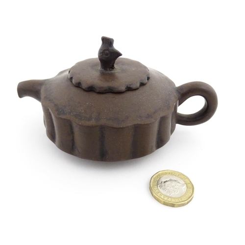 10 - A small Chinese Yixing teapot of lobed form, the lid with bird head finial. Character marks under li... 