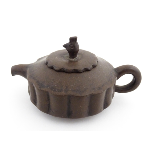 10 - A small Chinese Yixing teapot of lobed form, the lid with bird head finial. Character marks under li... 