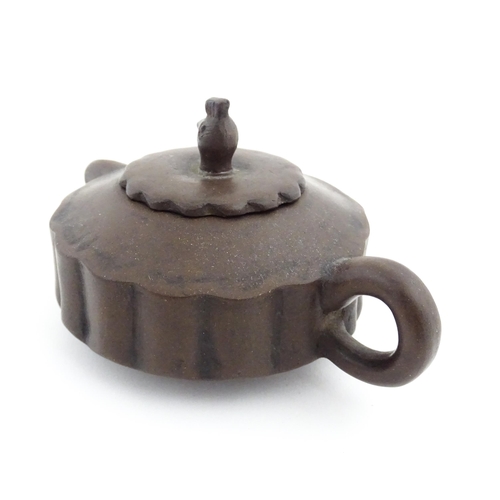 10 - A small Chinese Yixing teapot of lobed form, the lid with bird head finial. Character marks under li... 