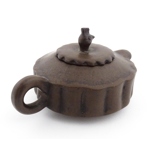 10 - A small Chinese Yixing teapot of lobed form, the lid with bird head finial. Character marks under li... 