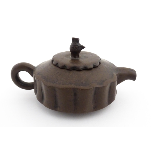 10 - A small Chinese Yixing teapot of lobed form, the lid with bird head finial. Character marks under li... 