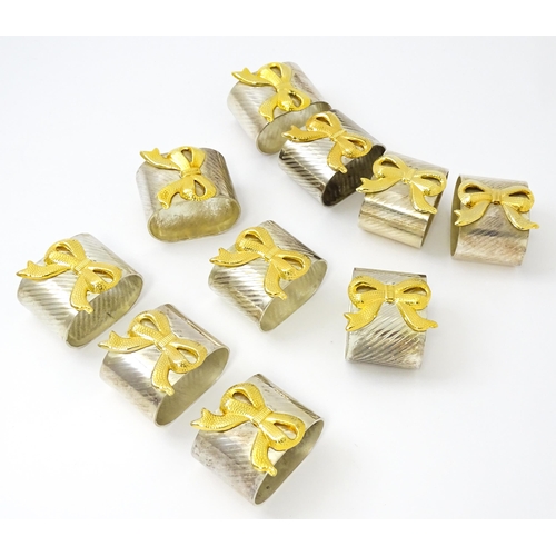 437 - Ten silver plate napkin rings with gilt bow detail.