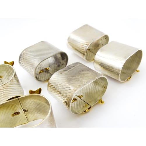 437 - Ten silver plate napkin rings with gilt bow detail.