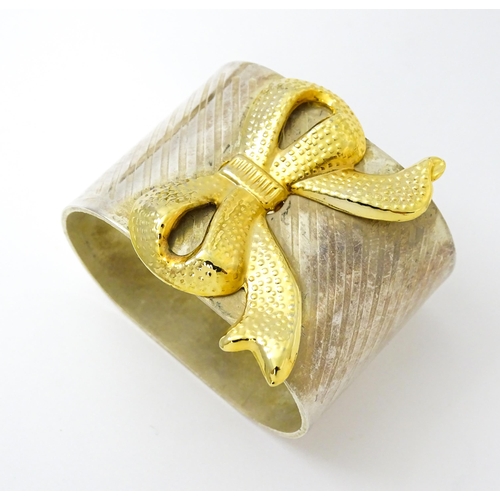 437 - Ten silver plate napkin rings with gilt bow detail.