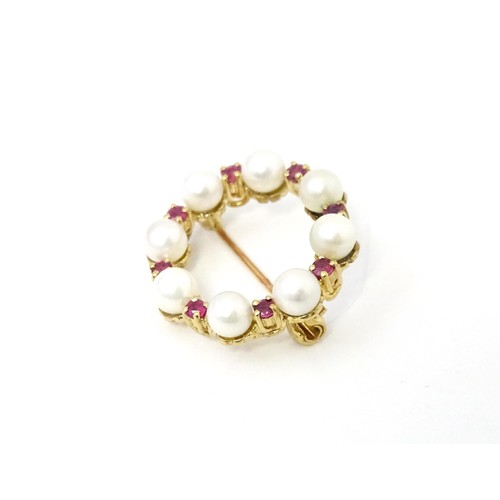 589 - A 9ct gold pendant / brooch of circular set with pearls and round cut rubies. Approx 1