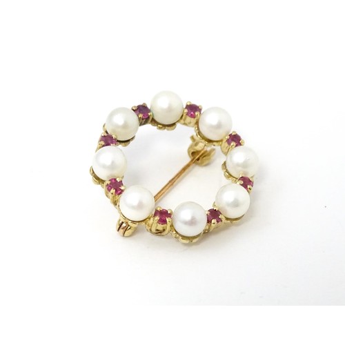 589 - A 9ct gold pendant / brooch of circular set with pearls and round cut rubies. Approx 1