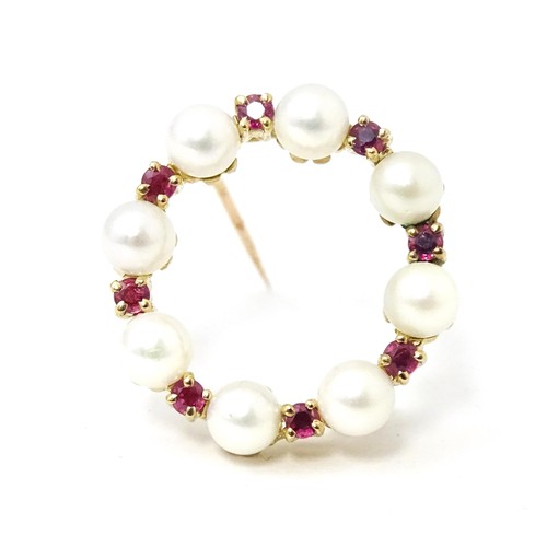 589 - A 9ct gold pendant / brooch of circular set with pearls and round cut rubies. Approx 1