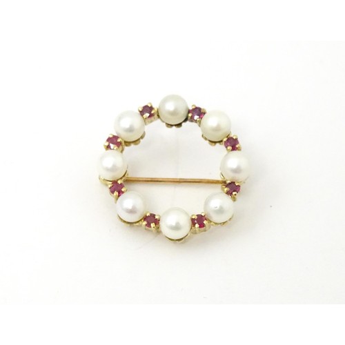 589 - A 9ct gold pendant / brooch of circular set with pearls and round cut rubies. Approx 1